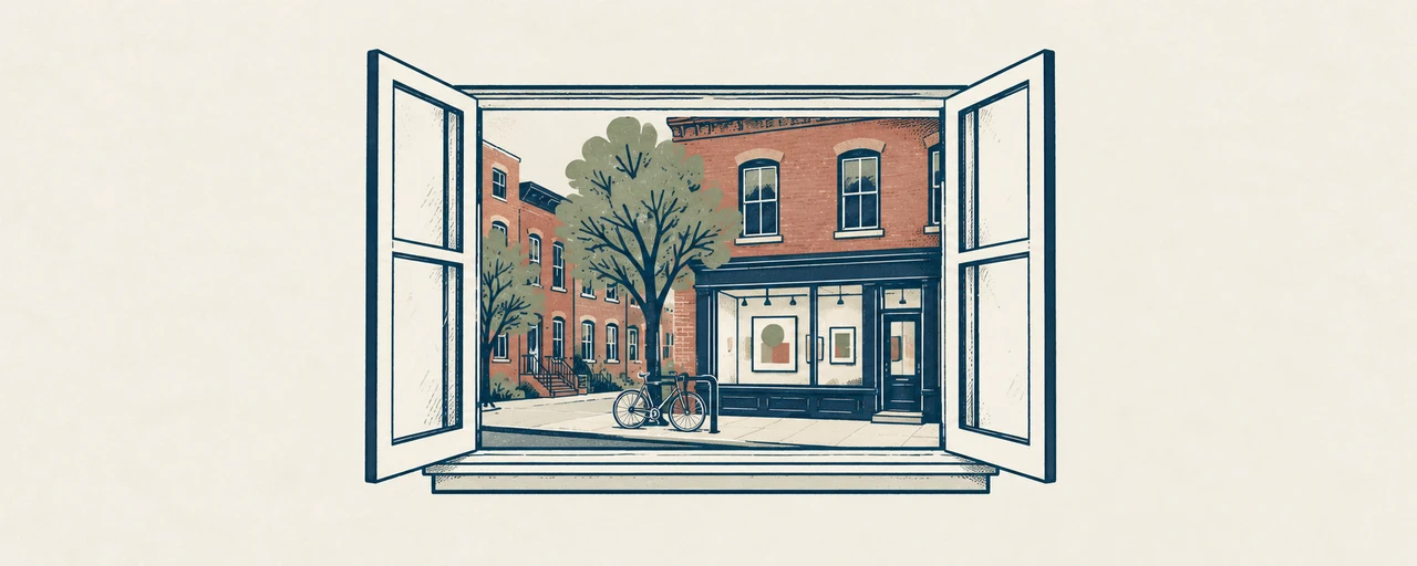 An open apartment window frames a red-brick neighbourhood with a gallery and a bicycle.